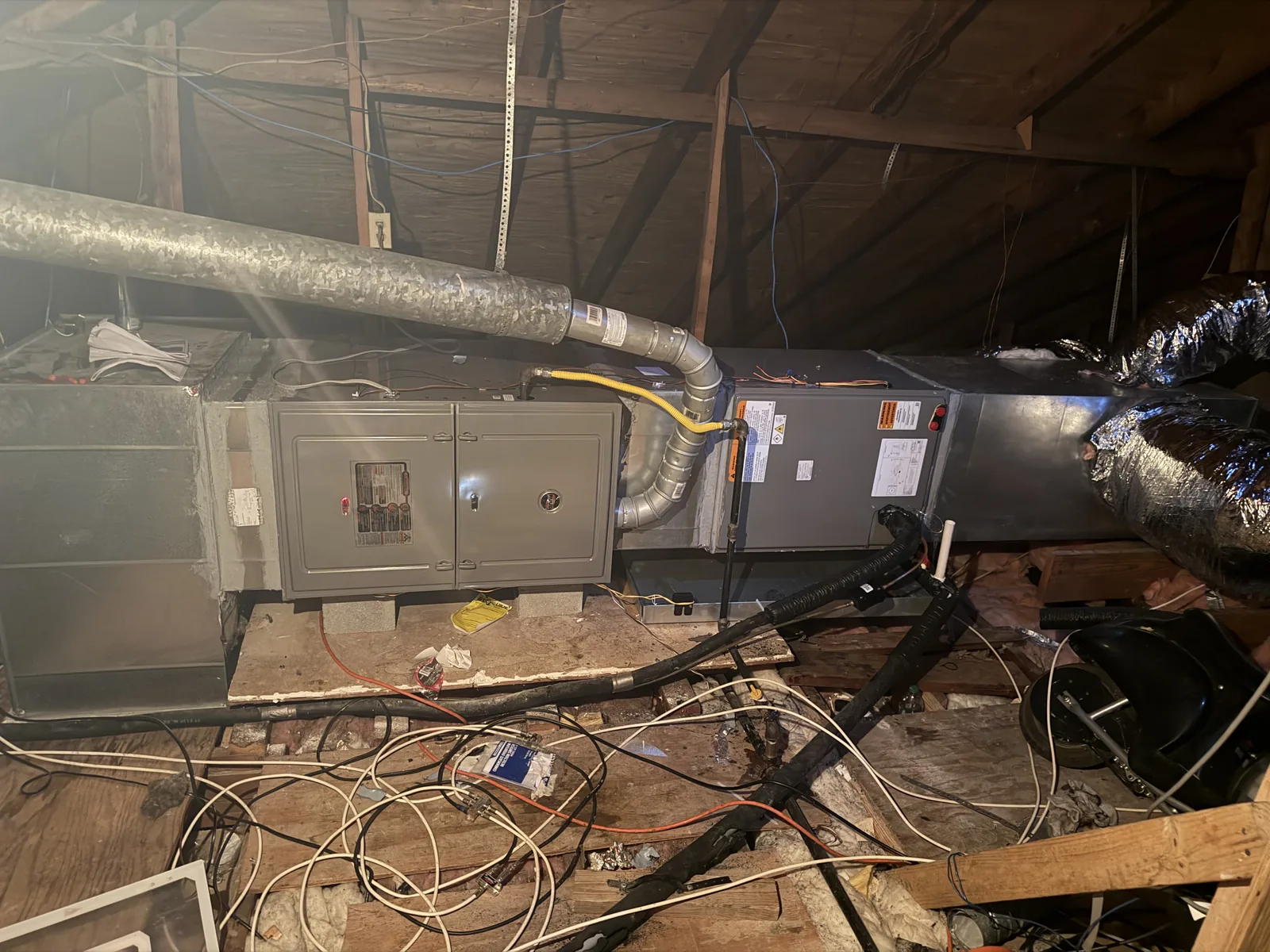 Attic air handler with electrical disconnect panels and insulated flex duct connections.