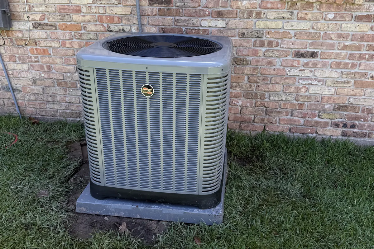 Outdoor air conditioning condenser unit beside a brick home in South Louisiana.